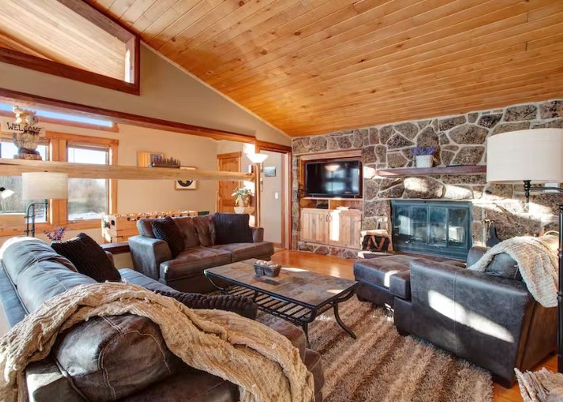 The living area of the 701B Quail townhome features comfortable seating, a stone fireplace, and abundant natural light.