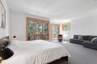 A bedroom with a large bed and a window that looks out onto a forest.