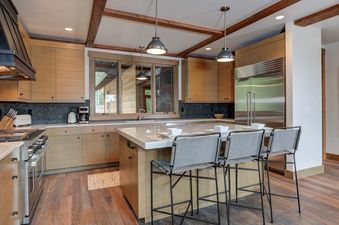 The kitchen at Moonlight Basin 6 Diversion Lane features stainless steel appliances, a large island with seating, and a view of the surrounding mountains.