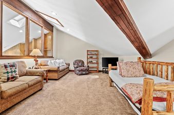 A cozy loft living area at Fairway Village 2919 with comfortable seating, a daybed, and rustic wooden accents under a sloped ceiling with a skylight.