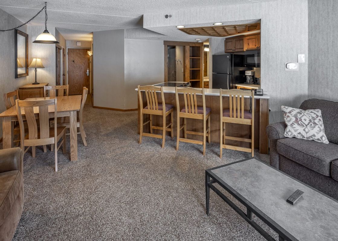 An inviting open-concept living area with a lounge, dining area, and kitchen in Building 4 One Bedroom Beaver Run Resort.