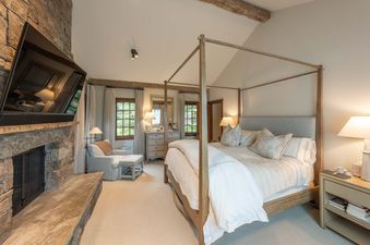 Elegant master bedroom at Shooting Star Cabin 05 with a wooden four-poster bed and stone fireplace.