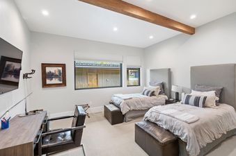 A modern bedroom at Fairway Cabin Four Bedroom Golf View features two twin beds, a desk area with a television, and a large window with outdoor views.
