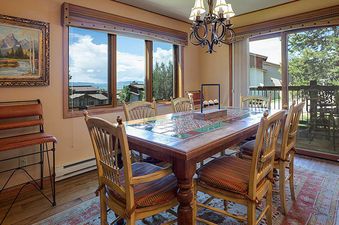 An inverted dining room at the Ranch at Steamboat RA201, featuring an upside-down dining table, chairs, and chandelier, with windows showcasing an exterior view.
