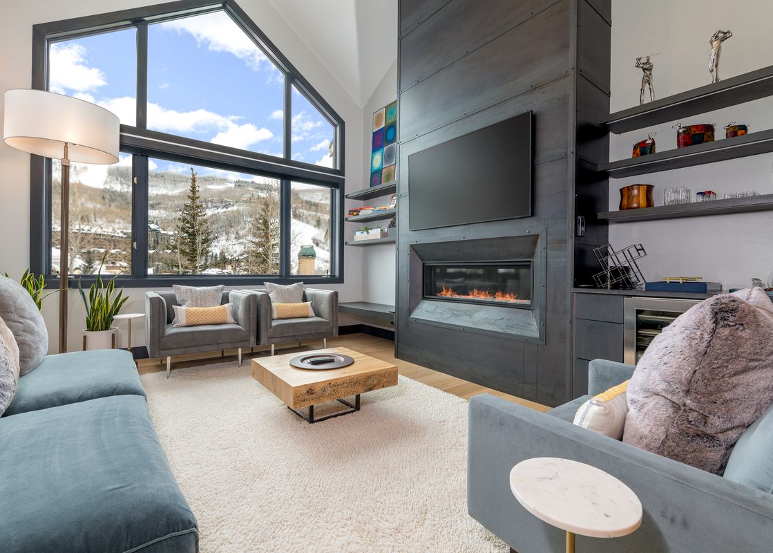 The stylish living area of Stone Creek Chalet at The Aspens boasts a modern fireplace and a beautiful view.