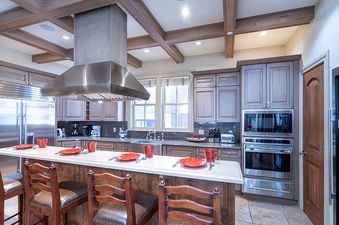 A large modern kitchen with stainless steel appliances and a large island with bar stools.