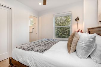 A bedroom at Abode at Kings Gold features a plush bed with plenty of pillows and a window.