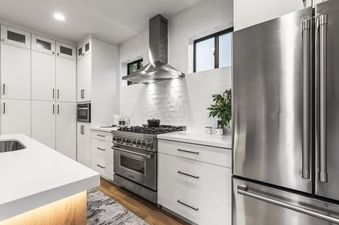Stainless steel appliances, white cabinets, and white tile backsplash in a modern kitchen.