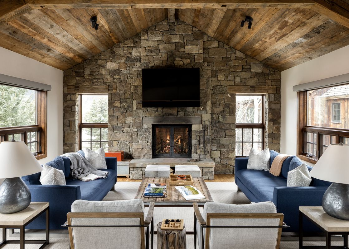 Elegant rustic living room in Shooting Star Cabin 01 with a large stone fireplace and vaulted wood ceiling.