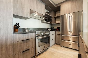 Stainless steel appliances, light wood cabinets, and a black granite countertop are seen in a modern kitchen.