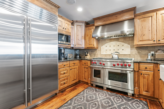 The stainless steel kitchen in Grand Lodge 3 Bedroom Deluxe 304 features a large refrigerator, a double oven, a microwave, and a dishwasher, plus a full set of pots, pans, and utensils, making it a dream to cook meals in.