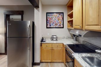 The kitchen in Manor Vail 165 features stainless steel appliances, granite countertops, a breakfast bar, and a full-sized refrigerator.