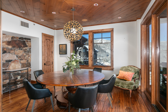 The dining room in Grand Lodge Three Bedroom 301 is well lit with a large window overlooking the snow-covered mountains and a wooden table with six chairs.