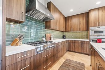 A modern kitchen at Pinnacle in Deer Valley features wood cabinetry, white countertops, and vibrant green tile backsplashes, creating a stylish and functional space.