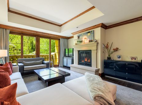 A spacious living room with a fireplace, large windows, and two couches.