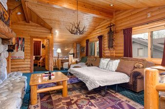 The cozy living room at Abode at Glenfiddich in Deer Valley features wood walls and exposed beams.