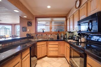A well-appointed kitchen in Chateau Chamonix CX133 with black granite countertops, wood cabinets, and modern appliances.