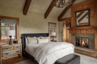 Cozy rustic bedroom at Hord Mountain Retreat featuring a fireplace, vaulted timber-beamed ceiling, and a comfortable bed.