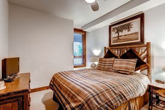 Cozy bedroom with a rustic log-frame bed and plaid bedding at BlueSky Breckenridge 204.