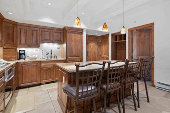 A kitchen with stainless steel appliances and a breakfast bar with four stools