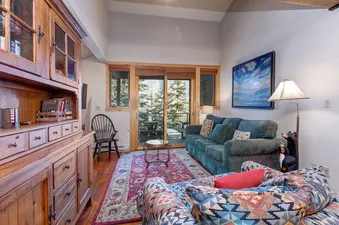 Living room with a couch, two chairs, a rug, and a wooden hutch.