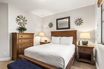 The primary bedroom features a king-sized bed, wooden furniture, and decorative wall art, with a large window providing natural light.