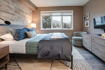 A cozy bedroom at Ranch at Steamboat RA511 with a large bed, wooden dresser, flat-screen TV, and a window offering a scenic winter view.