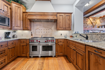 The kitchen in Grand Lodge Three Bedroom Deluxe 206 features stainless steel appliances, wooden cabinetry, granite countertops, and a breakfast bar.