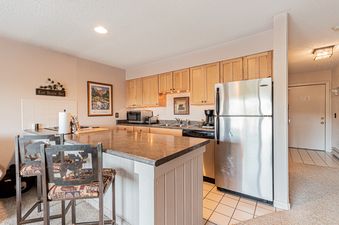 Kitchen with stainless steel appliances and a breakfast bar with two stools.