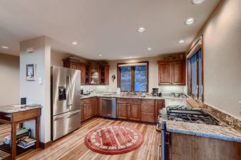 The kitchen at Ullr Haus features modern appliances and a view of the snowy outdoors.