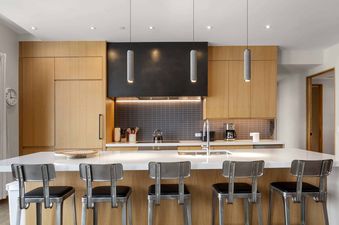 Modern kitchen in One Snowmass East 603 featuring a large island with bar stools and stylish wooden cabinetry.