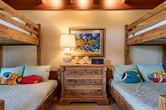 Cozy bunk room in Hale Hoaloha featuring rustic wooden bunk beds with colorful fish pillows.