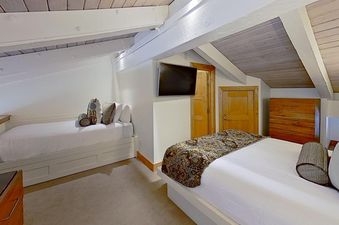 A cozy bedroom in Crestwood 2307 with two beds, a wall-mounted TV, and wooden accents.