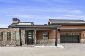 Modern mountain home exterior of SkyRidge 1307 featuring stone and wood siding under a blue sky.
