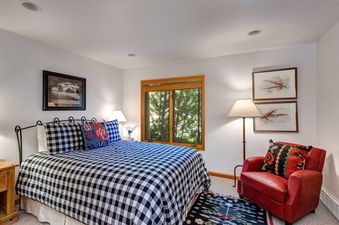 Bedroom at Deer Lake Village Abode with a cozy armchair and a black and white checkered bed.