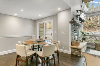 The dining area at Stonebridge 1158, featuring a glass dining table with six chairs, a sliding glass door to the outside, and a stone fireplace.
