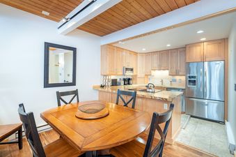 A kitchen with wood cabinets and stainless steel appliances in a condo with a dining area