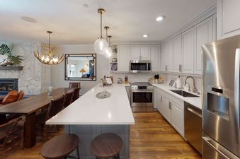 A modern kitchen with stainless steel appliances, white cabinets, and a large island with a breakfast bar.