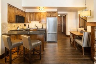 Kitchen and dining area of the Teton Mountain Lodge and Spa Sundance Junior Suite with wooden cabinetry and stainless steel appliances.