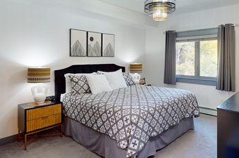 The bedroom in Canyon Creek B304 featuring a large bed, stylish nightstands, and a window looking out at trees.