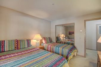 Two twin beds with colorful bedspreads in a bedroom with a mirrored closet.