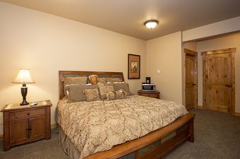 A cozy bedroom with a large bed, two nightstands, and two wooden doors.