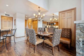 Woodrun Place 04 dining room with a table and six chairs, a fireplace to the right and an open doorway leading to the kitchen.