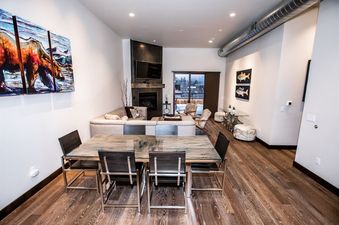 An open-plan living and dining area at 2nd Street Lofts 302, featuring modern furniture, a fireplace, and a balcony with mountain views.