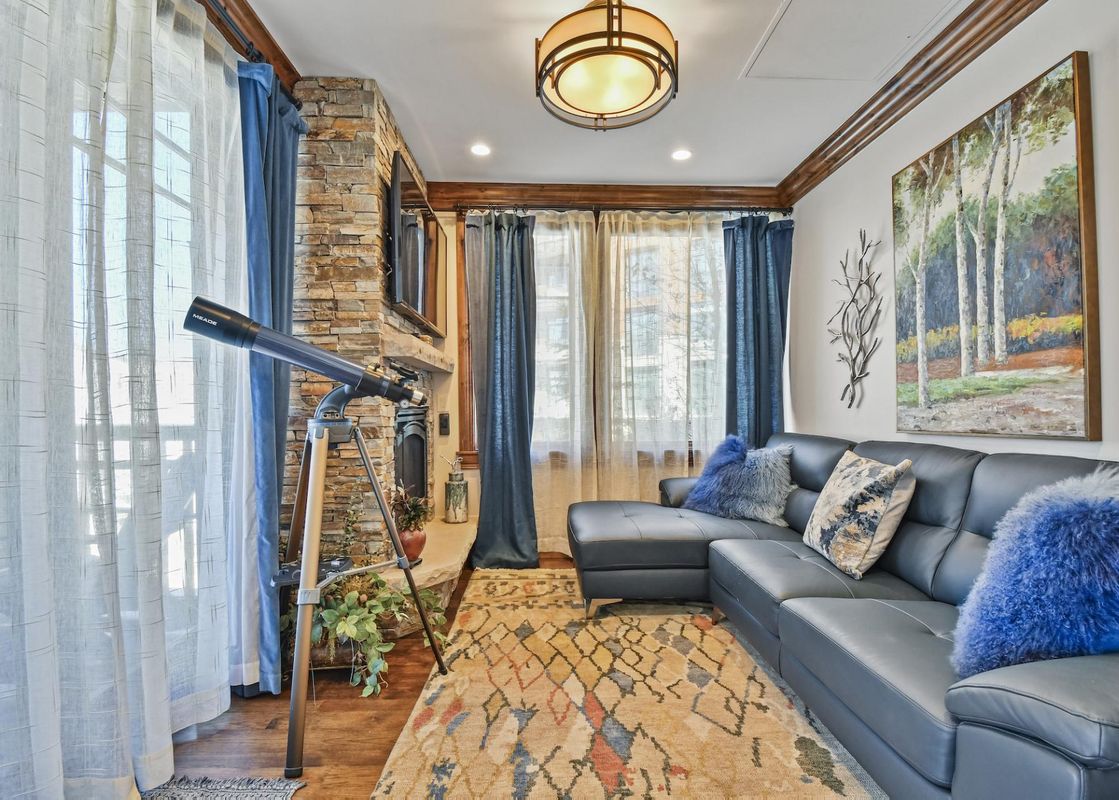 The inviting living room at Silver Strike Lodge 201, featuring a comfortable sectional sofa, a fireplace, and a telescope positioned by the window.