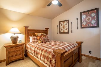 A bedroom with a wooden bed, a wooden nightstand, and a lamp