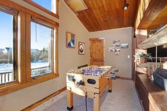 A bright room with a foosball table by a large window showing a snowy landscape, and a cozy seating area.