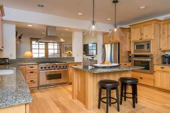 A modern kitchen with stainless steel appliances, wood cabinets, and a granite countertop.
