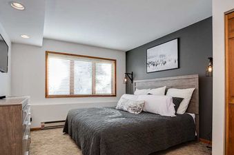A cozy bedroom in Ranch at Steamboat RA507 with a king-sized bed, dark gray accent wall, and a large window with blinds.