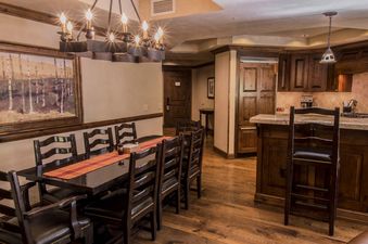 The dining area and kitchen of the Hyatt 4 Bedroom are elegantly designed with rustic wooden furniture and warm lighting.